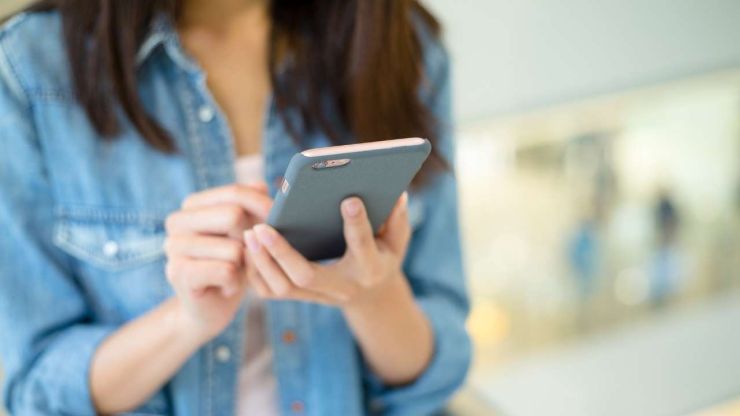 Sieviete telefonā lasa informāciju par kredītu refinansēšanas priekšrocībām